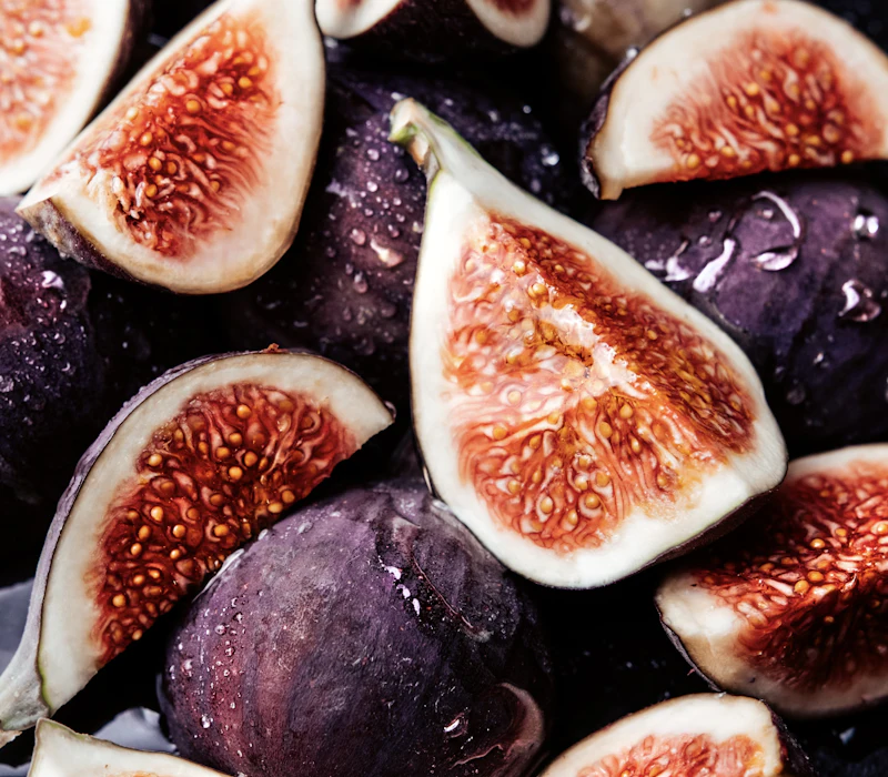 Halved black mission figs on a dark surface