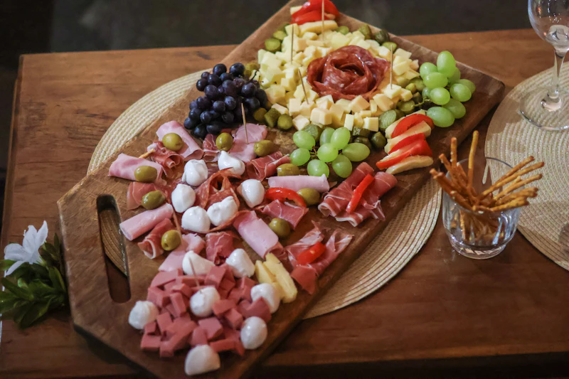 Abundant charcuterie board with salami, ham, fresh mozzarella, grapes and tomatoes