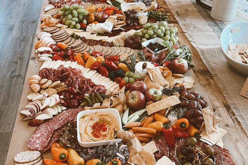 A long grazing table piled with cheeses, cured meats, fruit, crackers and dips