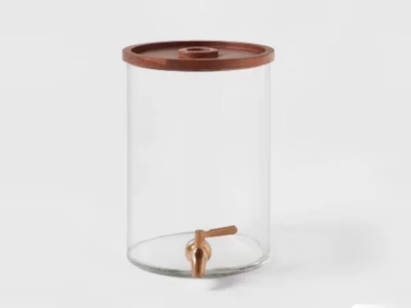 A clear glass beverage dispenser with a wooden lid and copper tap