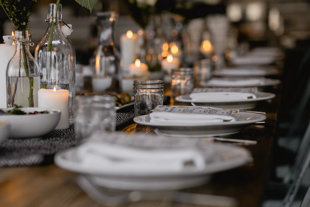 A long candlelit dining table set with white plates and glassware